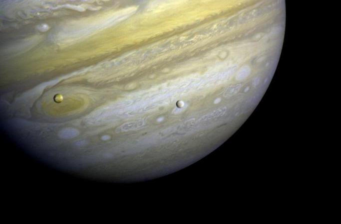 Close-up of the planet Jupiter with the moons Io on the left and Europa on the right
